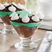 Two Acopa footed dessert glasses filled with whipped cream and chocolate.