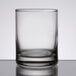 A close up of a clear Libbey shot glass with a silver rim on a table.