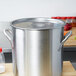 A large silver Stainless Steel Stock Pot Cover on a wooden surface.