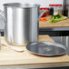 A large silver stainless steel Vollrath stock pot cover on a wooden surface.