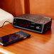 A black Conair alarm clock and a cell phone on a table.