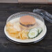 A Dart clear plastic dome plate cover over a plate with a hamburger and chips.