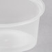 A close-up of a clear Newspring plastic oval souffle container with a lid.