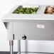 A stainless steel Advance Tabco hot food table with two pans of food on a counter.