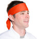 A man wearing an orange Intedge chef neckerchief on his head.