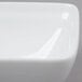 A close up of a white square bowl with a curved edge.