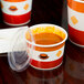 A Choice paper soup cup filled with soup and covered with a plastic lid.