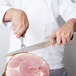 A person using a Mercer Culinary forged carving knife to slice meat.