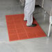A person standing on a red Cactus Mat anti-fatigue floor mat.