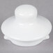 A white plastic lid with a round top on a gray surface.