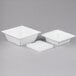 A Cal-Mil square porcelain bowl with a square bottom, triangle shaped center, and three white containers inside.