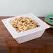 A white Cal-Mil square porcelain bowl with pasta and salad on a table.