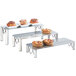 A row of Cal-Mil industrial rectangle risers with pastries on a table.