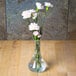 A clear Cambro bud vase with flowers on a table.