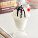 A glass of white ice cream with HERSHEY'S chocolate syrup being poured on top.