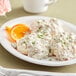 A white plate with biscuits and Vanee Old Fashioned Biscuit Gravy with a slice of orange.