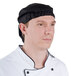 A man wearing a Chef Revival black chef head wrap and a white chef coat.