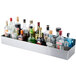 An Advance Tabco stainless steel double tier speed rail on a counter with bottles of liquor.