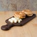 An American Metalcraft ash wood serving board with bagels and cheese on it.