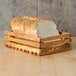 An American Metalcraft olive wood bread crate on a table with sliced bread inside.