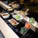 An American Metalcraft three-tier chrome display stand with a buffet of food on a counter.