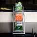 An American Metalcraft chrome three-tier display stand holding glass jars of vegetables.
