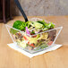 A salad in an American Metalcraft clear styrene bowl on a counter.