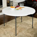 A Lifetime white plastic round fold-in-half table with food on it including sandwiches and chips.