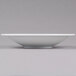 A CAC Super Bright White porcelain bowl on a gray surface.