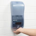 A hand using a San Jamar Rely Arctic Blue touchless soap, sanitizer, and lotion dispenser.
