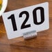 A white table card holder with black numbers next to a bowl of salad.
