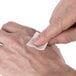 A person using Medi-First alcohol wipes on their hand.