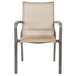 A tan Grosfillex outdoor stacking armchair with metal legs.