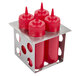 A group of red hot sauce bottles in an Eagle Group stainless steel holder.