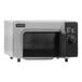 An Amana commercial microwave with a stainless steel and black finish and dial controls.