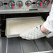 A person in white gloves using a Chicago Metallic glazed aluminized steel sheet cake pan to bake a tray of dough.