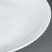 A close up of a CAC white bone china coupe plate with a white rim.