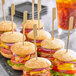 A group of burgers on a tray with Royal Paper Bamboo Paddle Picks.