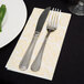 A knife and fork on a white Lavex Linen-Feel Elite guest towel.