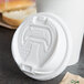 A Dart white paper cup lid with a reclosable tab on a white cup.
