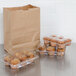 A group of muffins in plastic containers next to a Duro brown paper barrel sack.