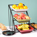 A Cal-Mil black square bowl display stand holding a tray of fruit and bread on a hotel buffet table.