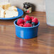A Fiesta Lapis china ramekin filled with raspberries and blueberries on a white table.