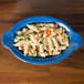 A blue Fiesta oval baker filled with pasta and vegetables.