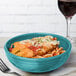 A Fiesta turquoise china bistro bowl filled with food and a fork next to it.