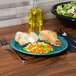 A piece of fried chicken on a turquoise Fiesta® dinner plate with vegetables.