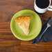 A slice of pie on a green Fiesta® appetizer plate next to a cup of coffee.