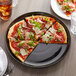 A Tuxton black china pizza serving plate with a slice of pizza with meat and cheese on it.