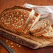 Close-up of sliced bread with oat flakes and seeds on a cutting board.