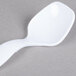 A white plastic spoon on a gray surface.